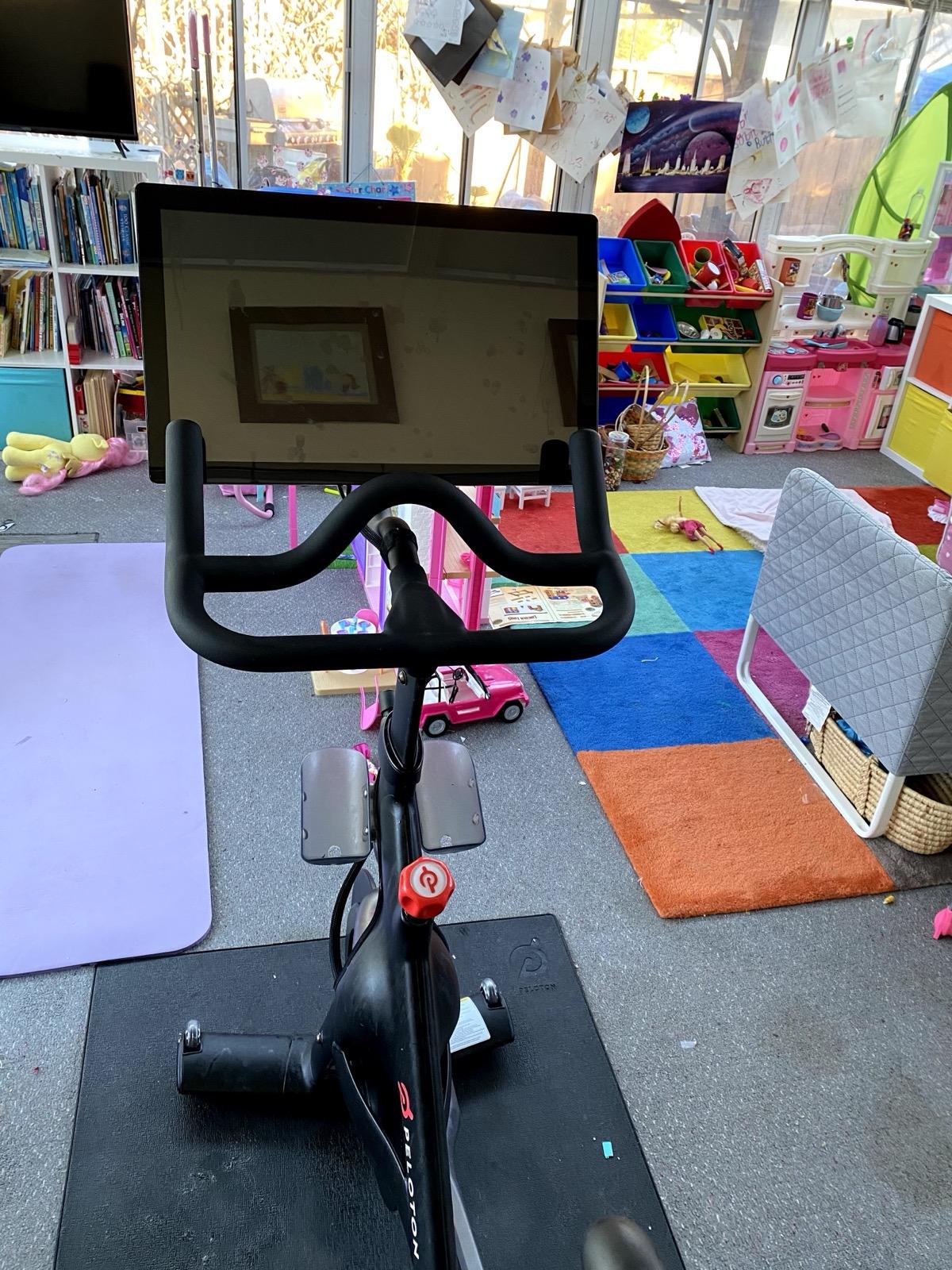 The view from a Peloton in 2021: the bike screen dark, a child’s playroom beyond it.